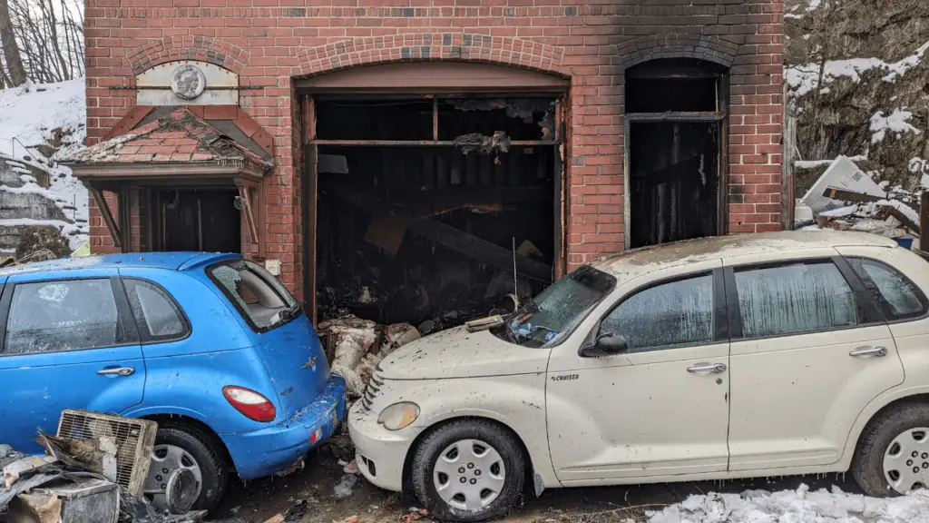 The exterior of the historic brick building looks OK but inside, severe damage is visible on the first and second floors. Two vehicles immediately in front of the building sustained minor damage.