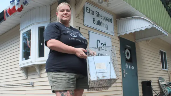 Sherrie Schafer, shelter manager at Hillside SPCA, holds a feral cat trap that could be used as part of a TNR program.